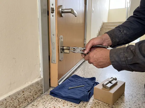 Cerrajero extrayendo un cilindro europeo dañado de la cerradura de una puerta